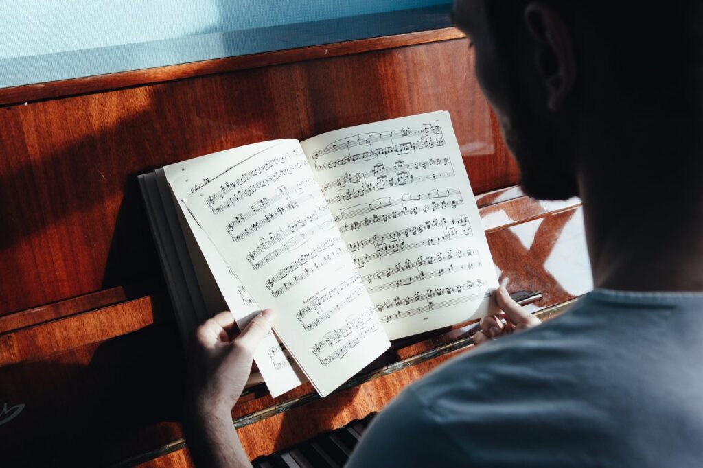 unrecognizable musician watching sheet music in classroom